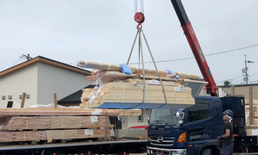 クレーン車を使って建材を荷卸しする様子